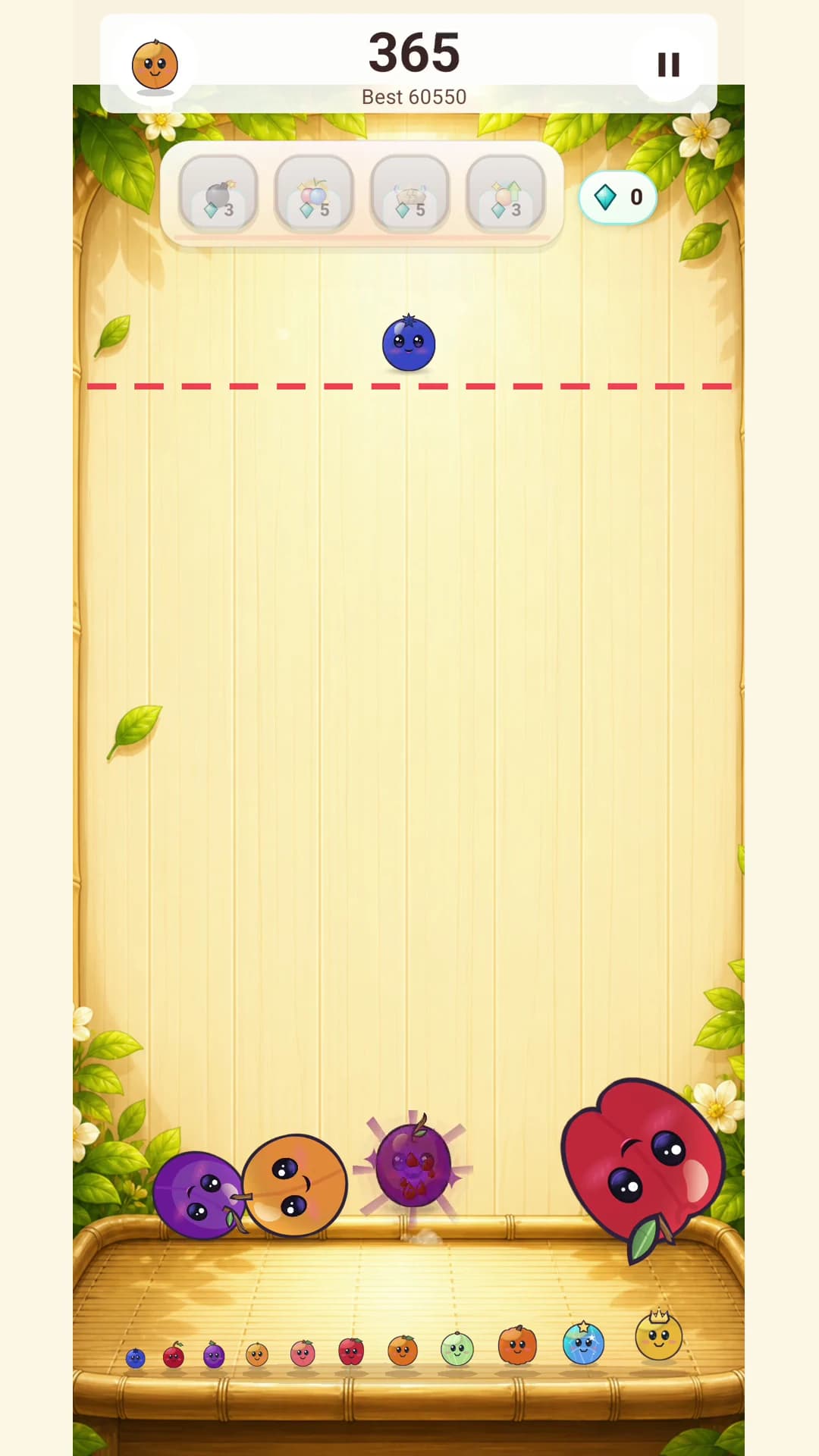 Fruit Fall board mid-session with a power-up row, a blueberry above the dashed danger line, and merged fruit resting on the tray